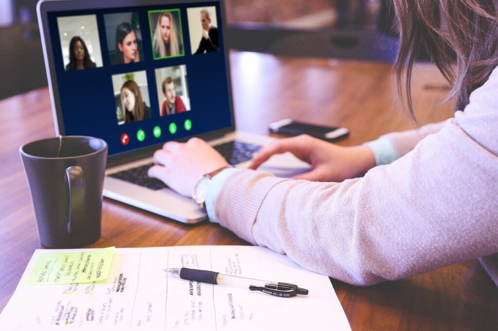 Das Bild zeigt eine Person, die an einer Videokonferenz mit ihrem Notebook teilnimmt